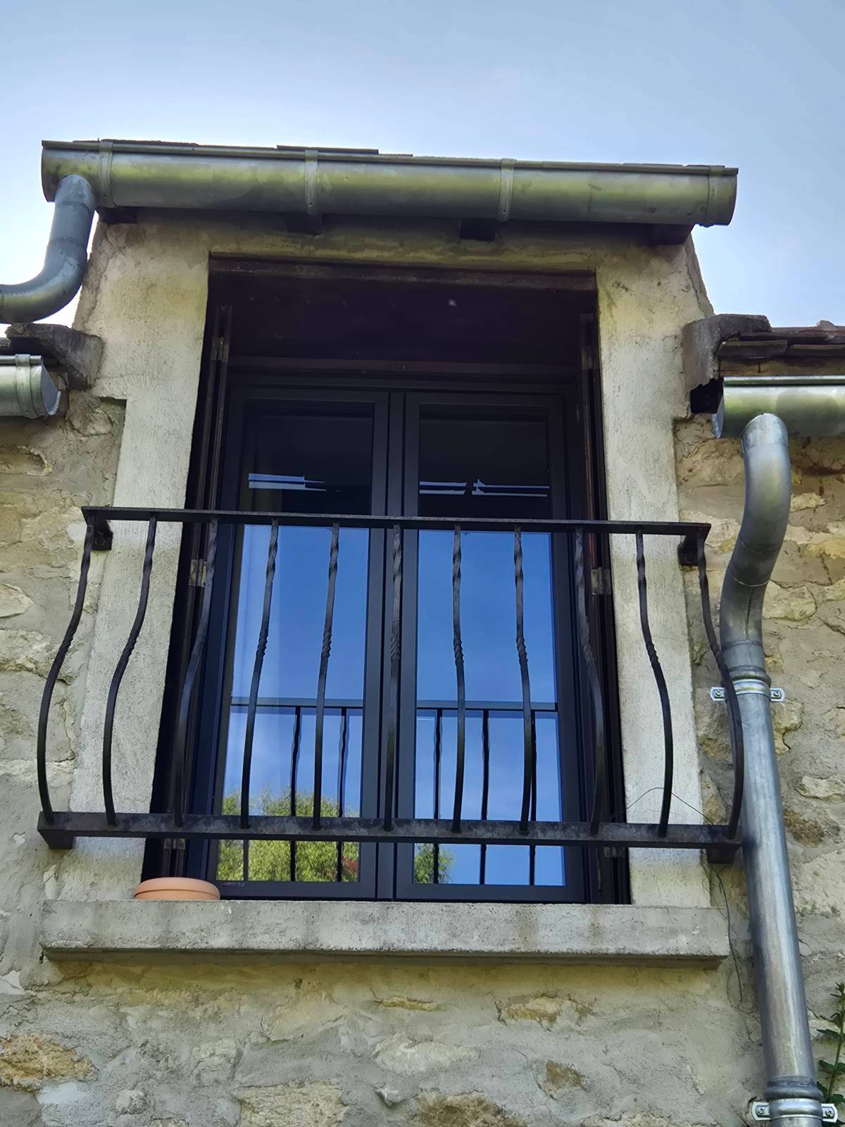 Fenêtre aluminium noire sur façade pierre