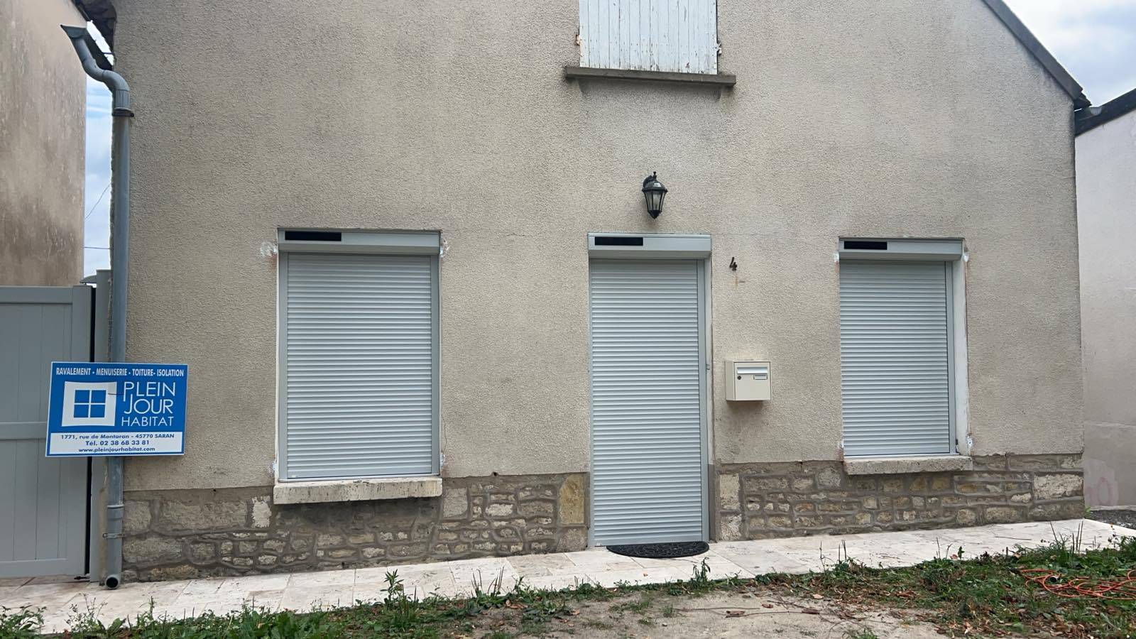 Volets roulants blancs sur façade pierre
